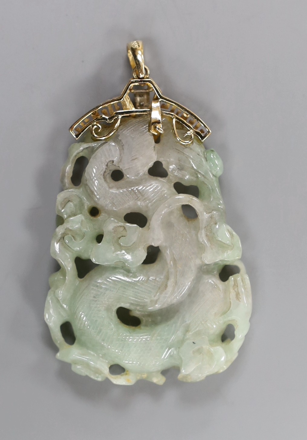 A Chinese jadeite Dragon pendant, the yellow metal mount stamped 14 K and set with diamond chips, overall 75mm, gross weight 31.4 grams.